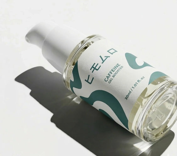 Serumflaska med pump, grönvit etikett, texten Caffeine Gel Booster, på vit bakgrund