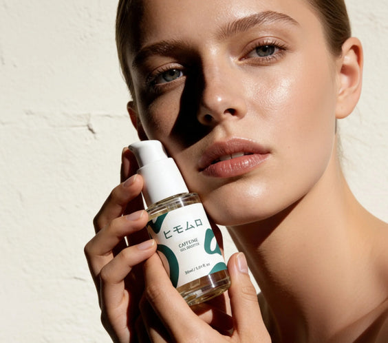 Kvinna med glödande hud håller en flaska Caffeine Gel Booster serum framför ansiktet