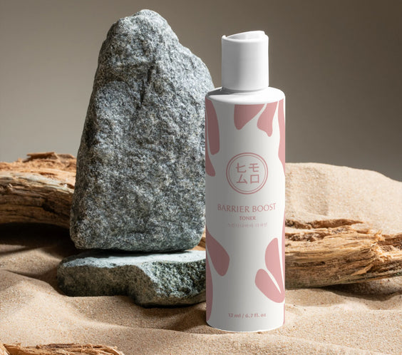Barrier Boost toner på sand med stenar och drivved, koreansk hudvård inspirerad produktfoto