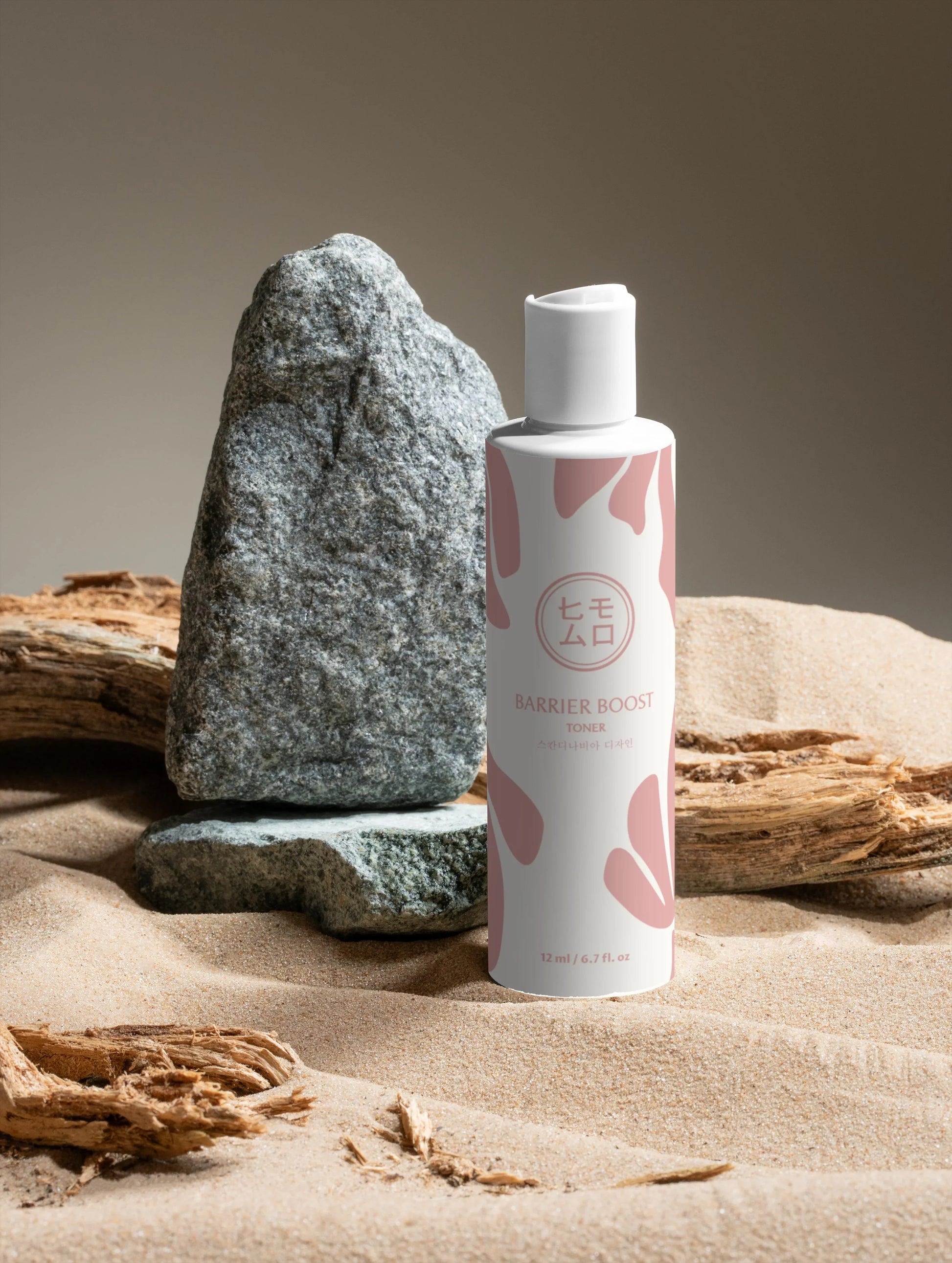 Barrier Boost toner på sand med stenar och drivved, koreansk hudvård inspirerad produktfoto